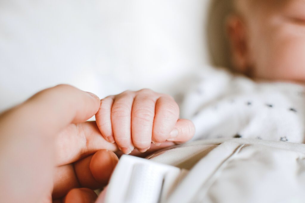 Prezent na narodziny dziecka - mama trzyma dziecko za rączkę.