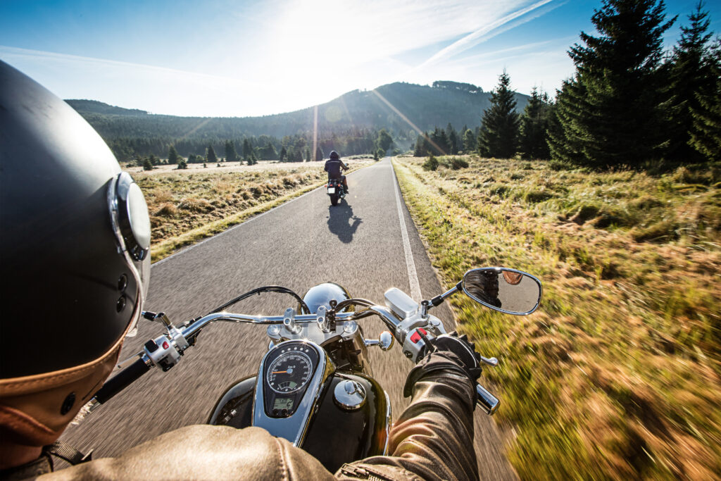 Wyprawa motocyklowa: jazda motocyklem po wąskiej uliczce, piękny widok na góry, świecące słońce