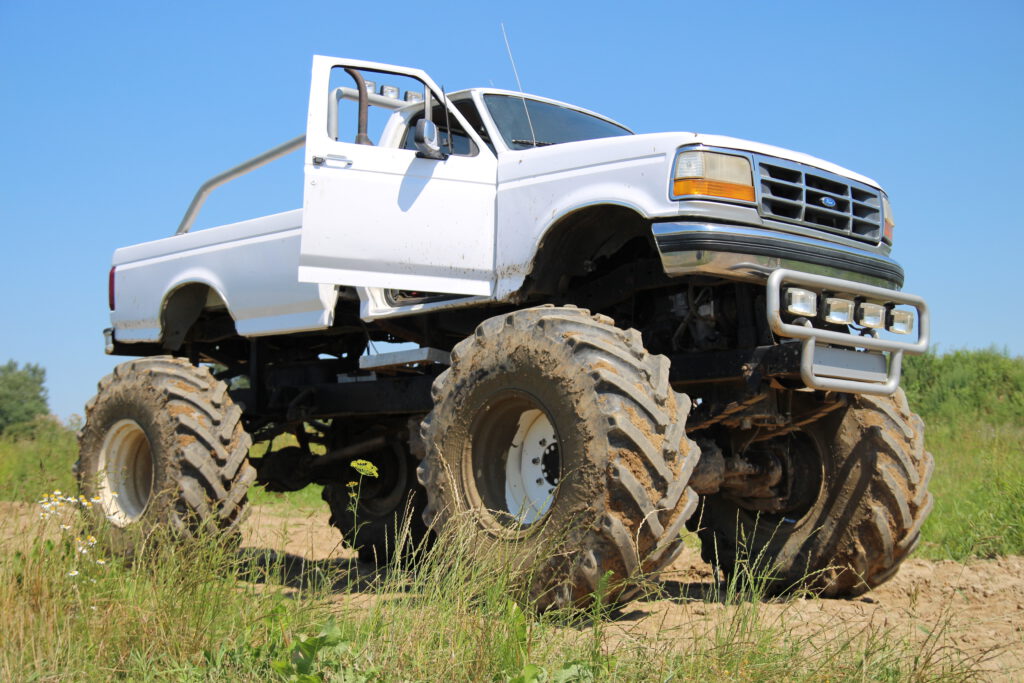 Przejazd Monster Truckiem - biały Monster Truck z otwartymi drzwiami od strony pasażera, widok z przodu