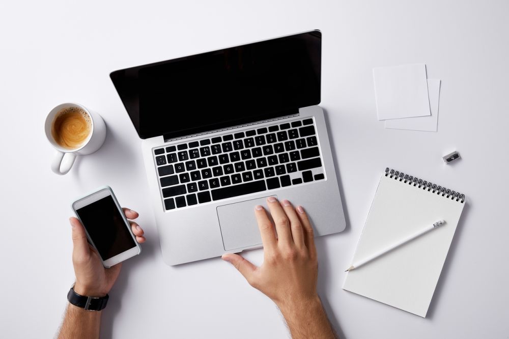 Biurko z laptopem, smartfonem, kawą i notatnikiem – miejsce do nauki języka online lub pracy zdalnej, symbol produktywności i nowoczesnej edukacji.